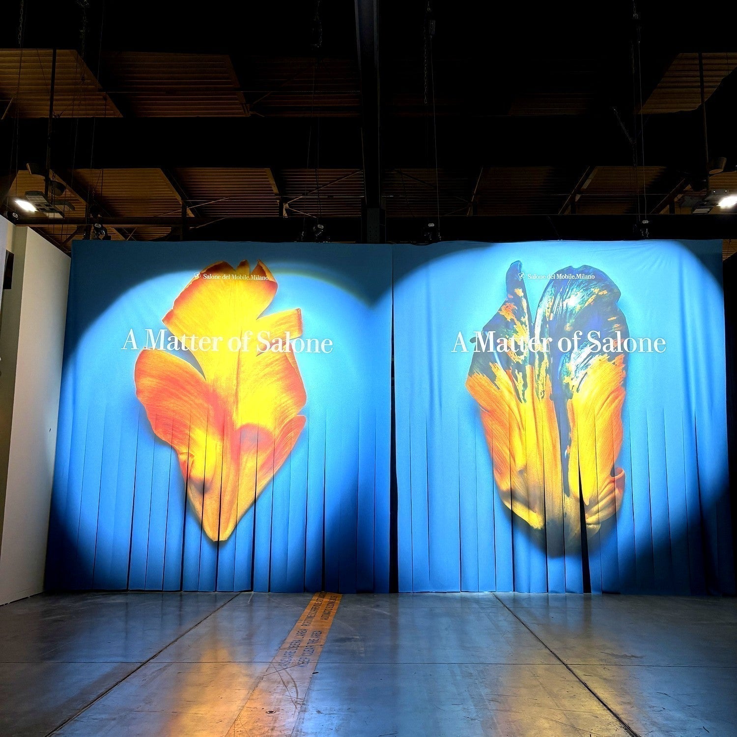 Two blue fabric banners with orange and yellow flower petals and the words A Matter of Salone