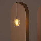 A glowing pendant of layered translucent glass on a black cord, hanging in a tall arched doorway