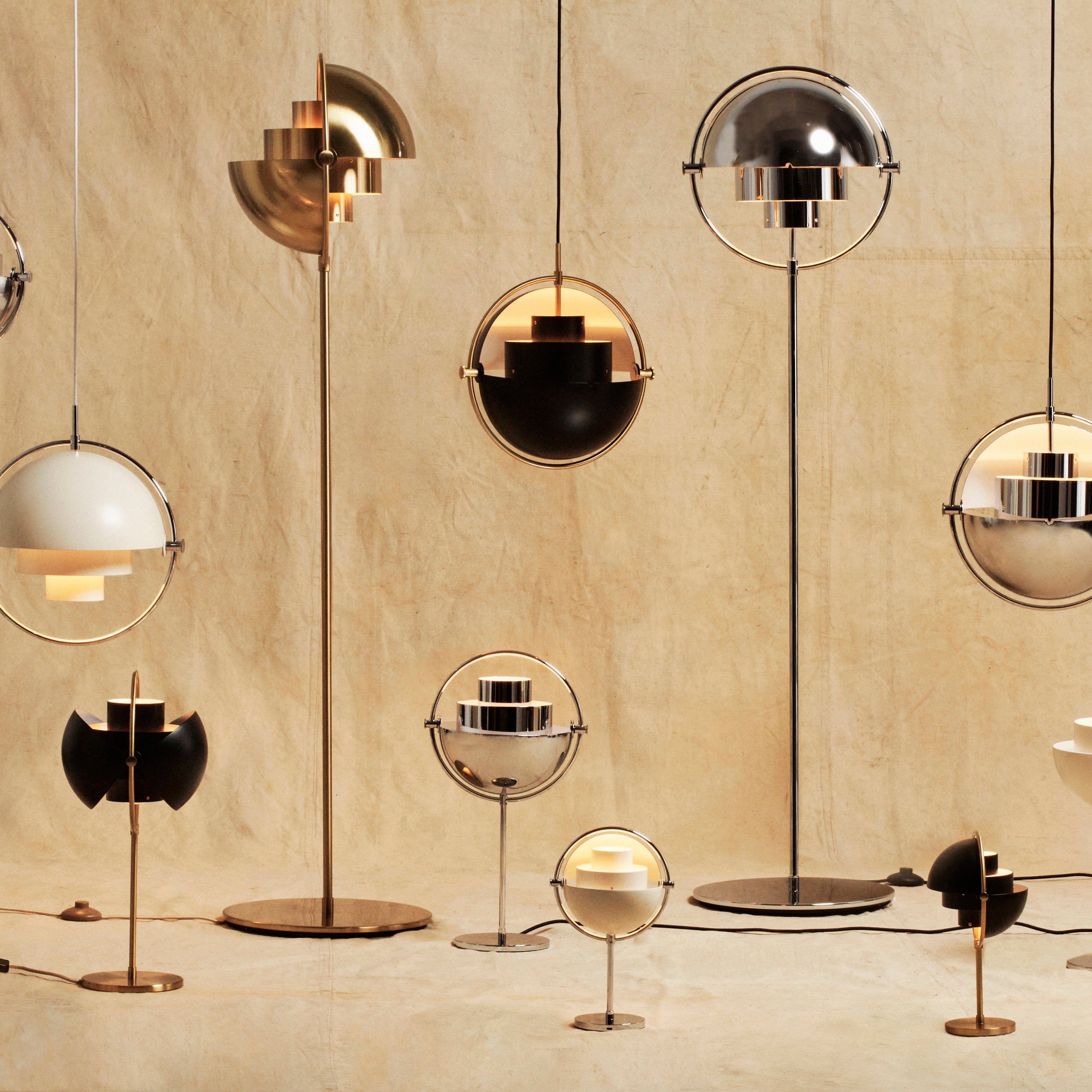 A group of floor, table and pendant lamps with half-dome shades in brass, chrome, black and white