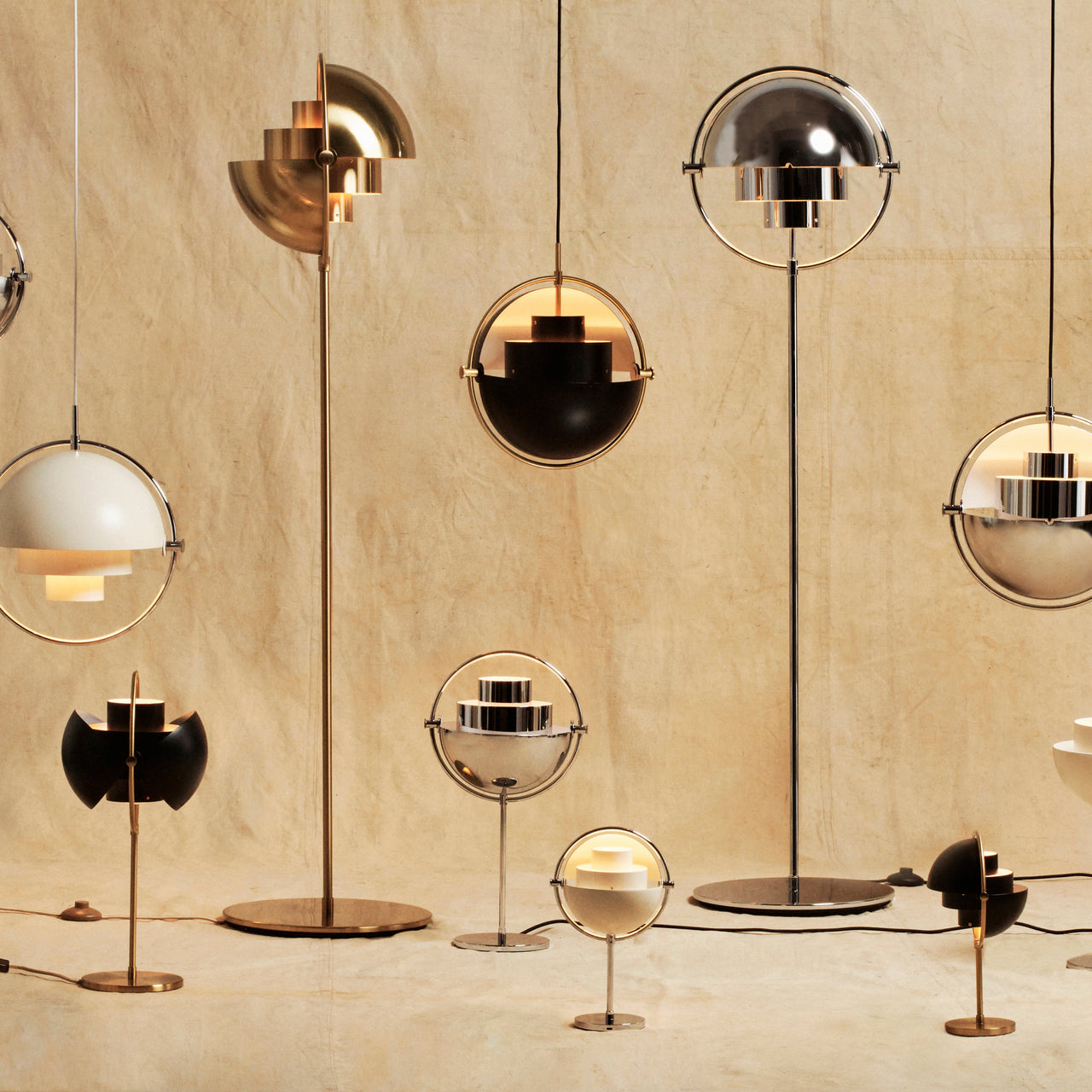 A group of floor, table and pendant lamps with half-dome shades in brass, chrome, black and white