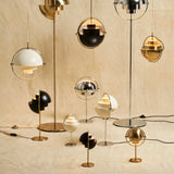 A group of round-shaded lamps in black, white, brass and chrome, standing and hanging on a canvas backdrop