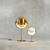 Two glowing table lamps with half-dome shades, one tall in polished brass and a smaller one in white and chrome