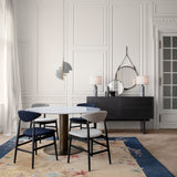 A dark wood sideboard with drawers and two marble lamps, beside a round dining table with four chairs