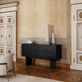 A black sideboard with four drawers and slab legs in an ornate room with gilded doors