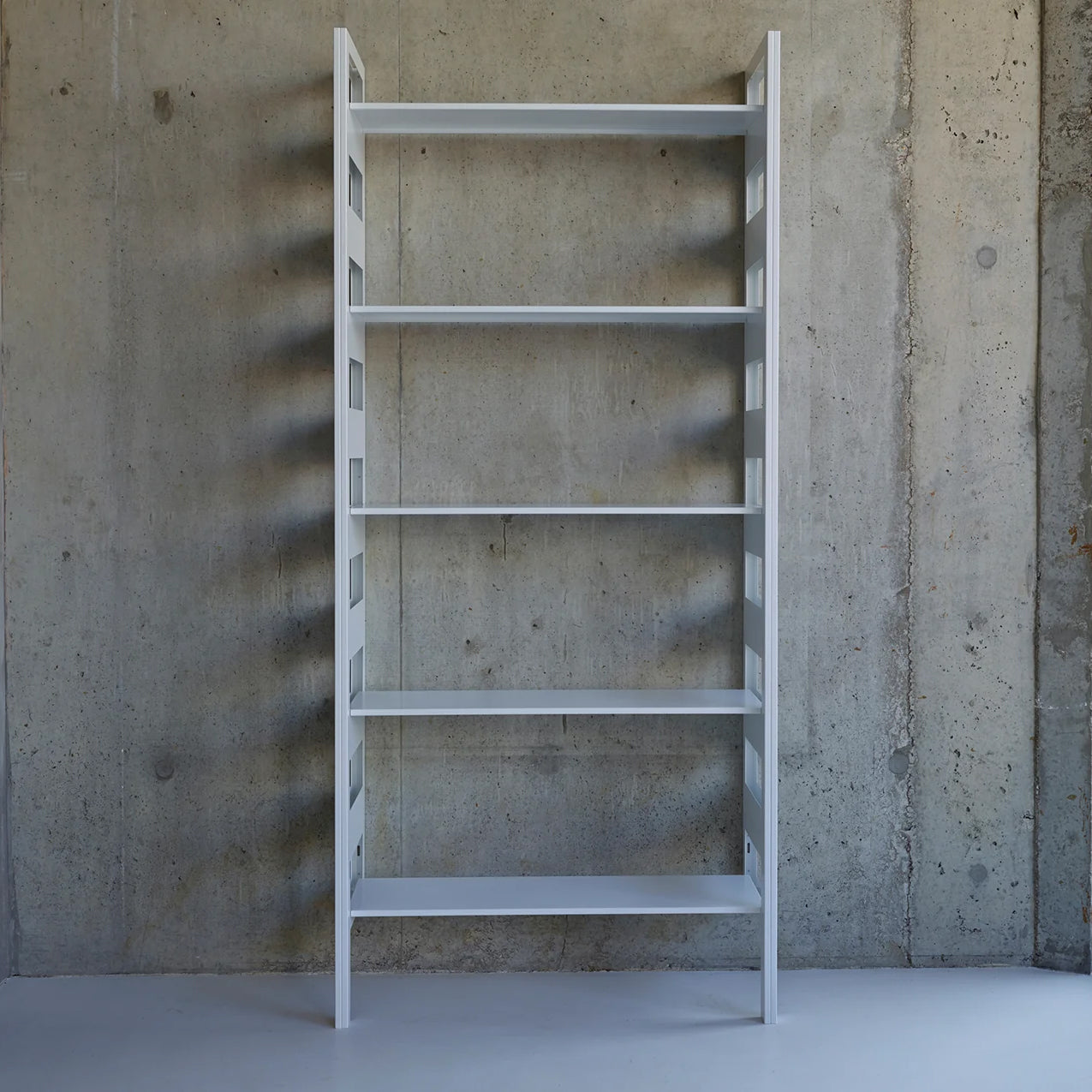 White ladder bookshelf against a concrete wall