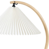 Close-up of a white pleated cone shade hanging from a curved light wood arm with a black fitting