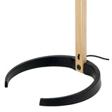 Close-up of a floor lamp's open black cast metal ring base holding a light wood upright with a black cord