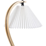 Close-up of a lamp with a white pleated conical shade hanging from a curved light wood arm with a dark stripe