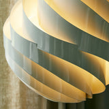 Close-up of a glowing pendant shade made of overlapping curved pale grey slats, lit warmly from within