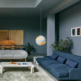 A white spherical pendant of overlapping twisted slats glows above a blue sofa in a grey-blue living room