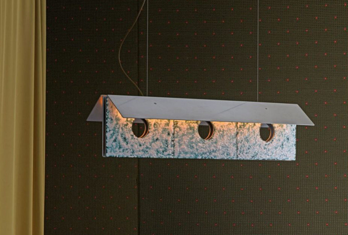 Modern pendant light fixture on a dark wall with a grid pattern