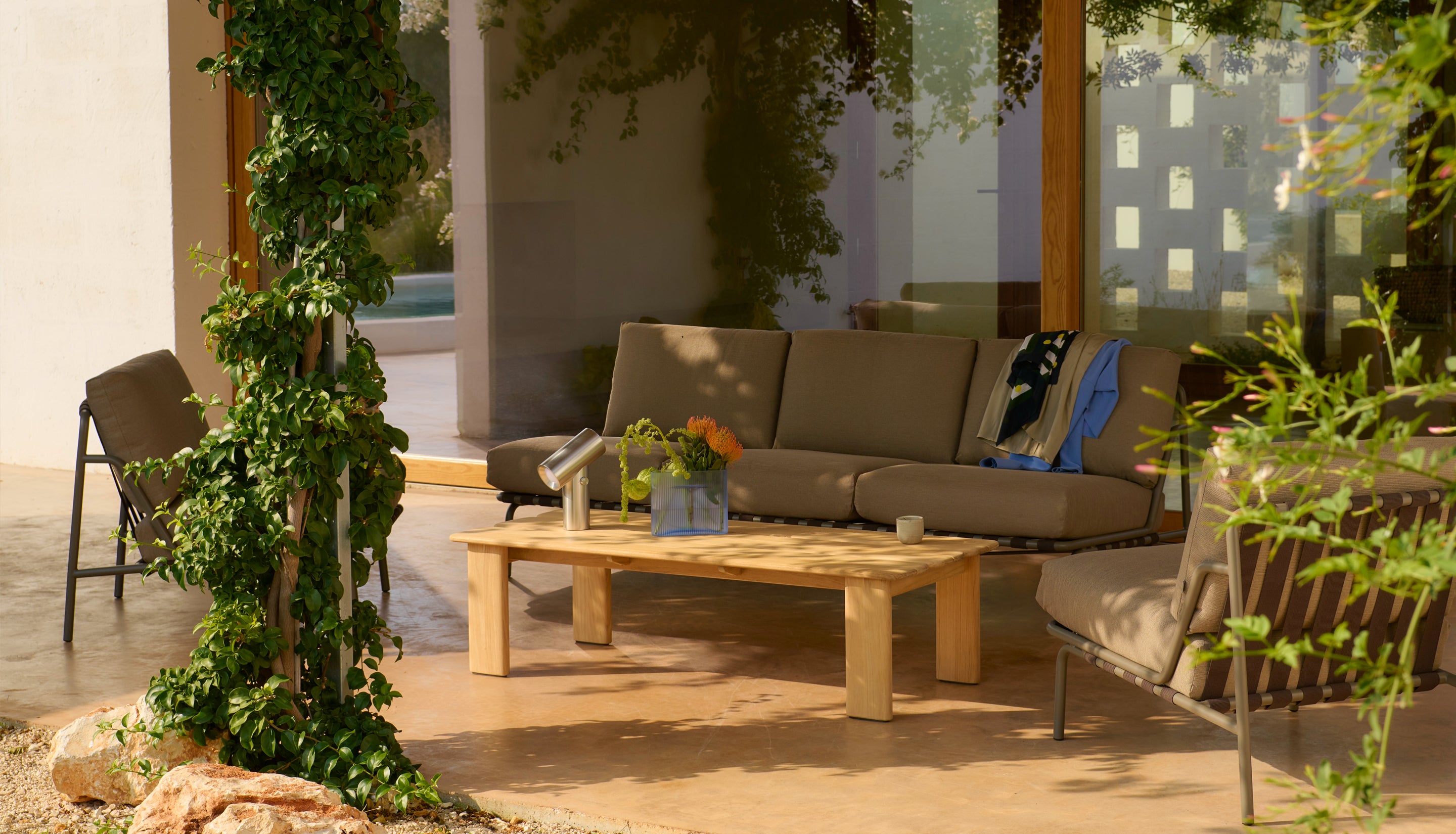 Outdoor patio with gray sofa, wooden coffee table, and decorative elements.
