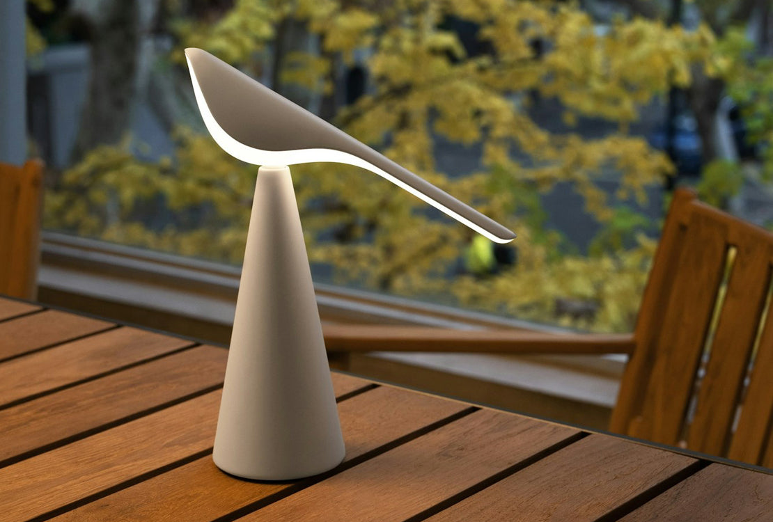 Modern outdoor lamp with a spoon-like design on a wooden surface
