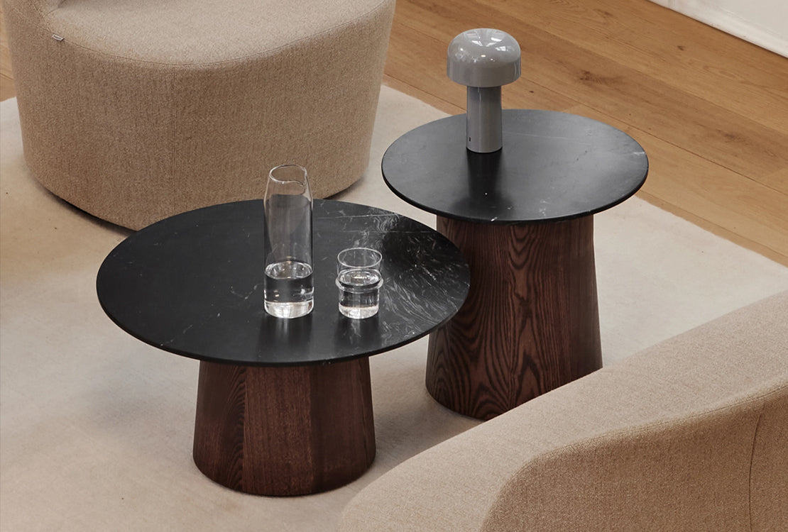 Two round coffee tables between seats with a lamp and glasses of water