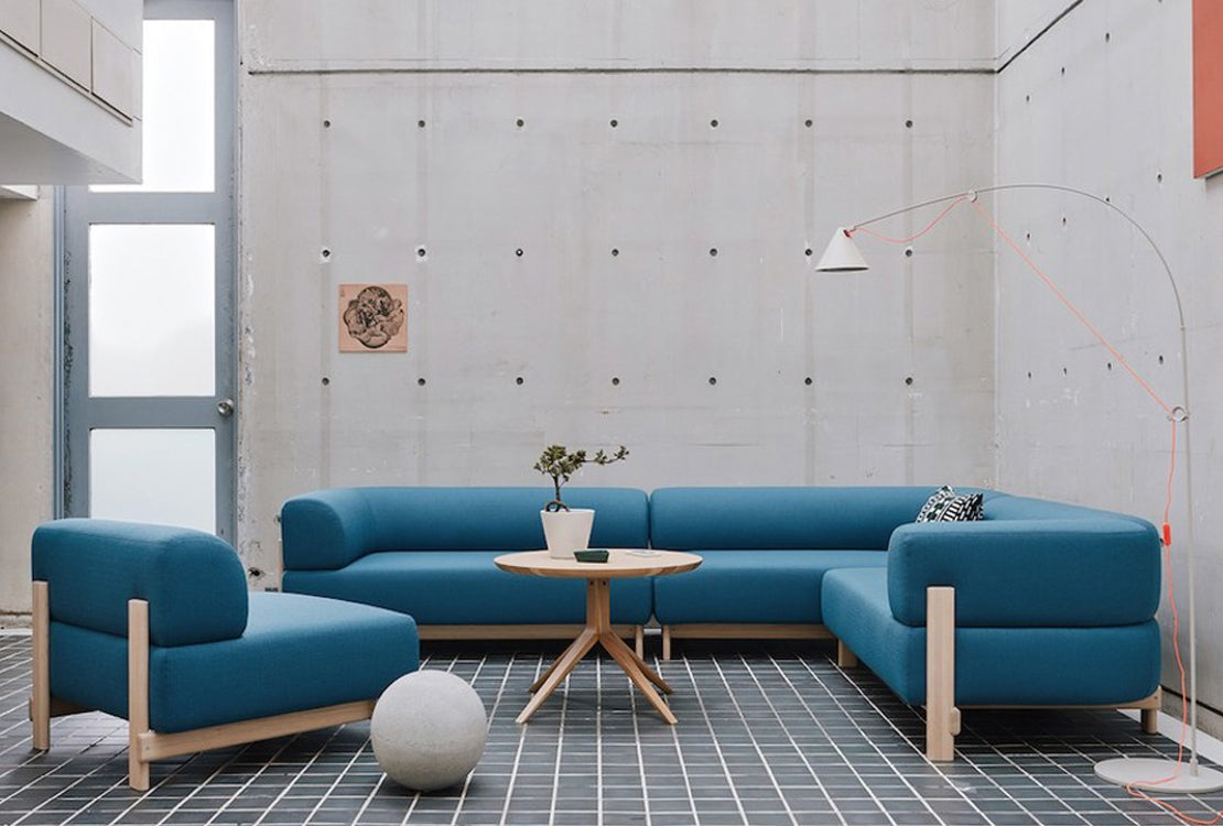 Blue sofa set in a modern room with concrete walls and a small round table.