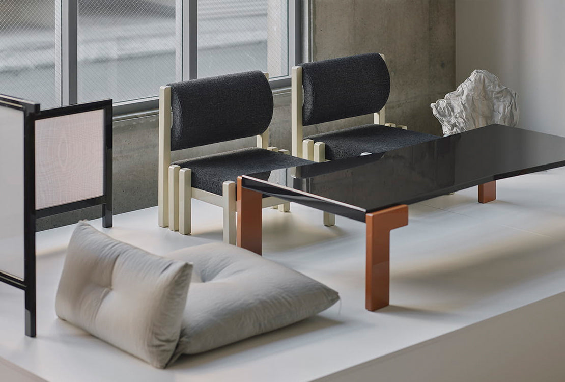 Modern furniture set with chairs, a table, and a cushion on a light floor.