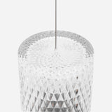 Close-up of a clear cylindrical glass pendant with a diamond-cut pattern, hung from a thin steel cable