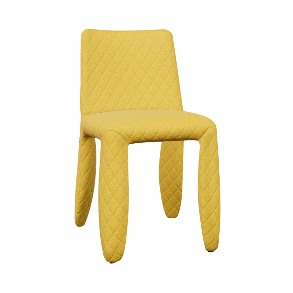 A mustard yellow chair covered in diamond-quilted fabric, with a rounded back and thick padded legs