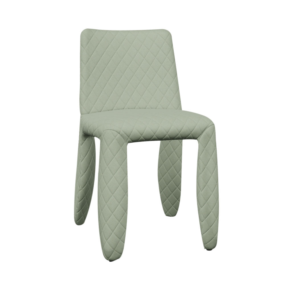 A pale sage green dining chair fully covered in diamond-quilted fabric, with thick rounded legs