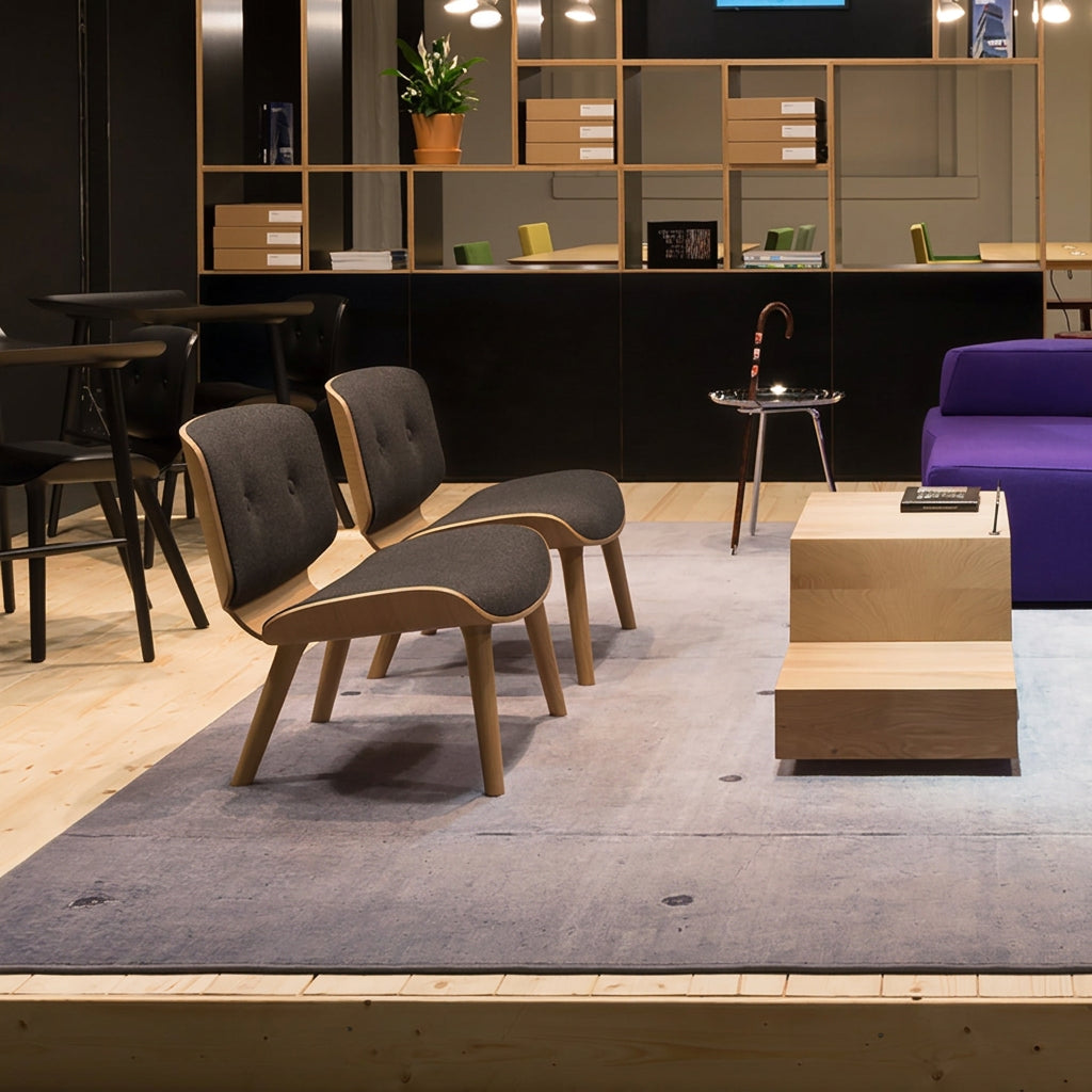 Two low lounge chairs with light wood frames and buttoned dark grey seats on a grey rug