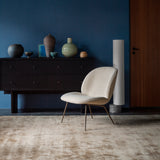 A dark wood sideboard with six drawers against a deep blue wall, with a cream patterned chair in front